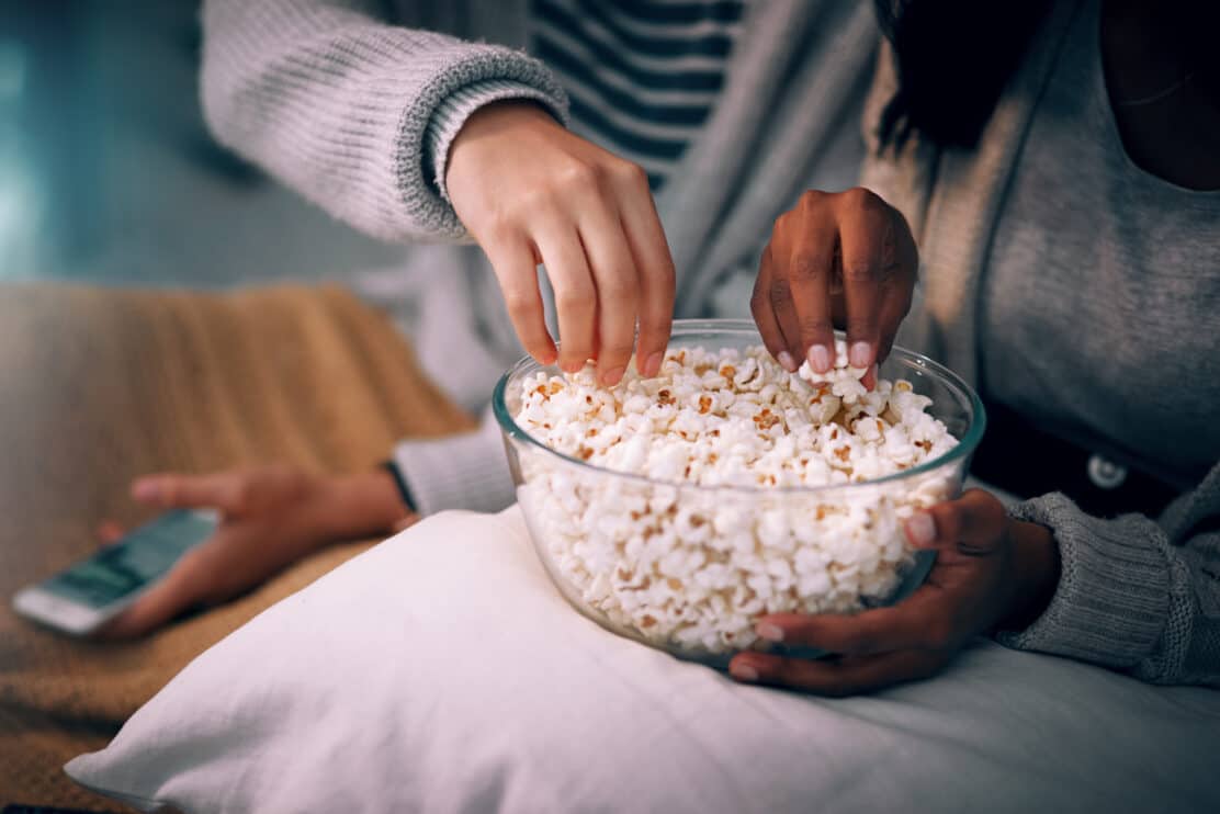 cropped-shot-of-two-unrecognizable-women-eating-popcorn-at-home