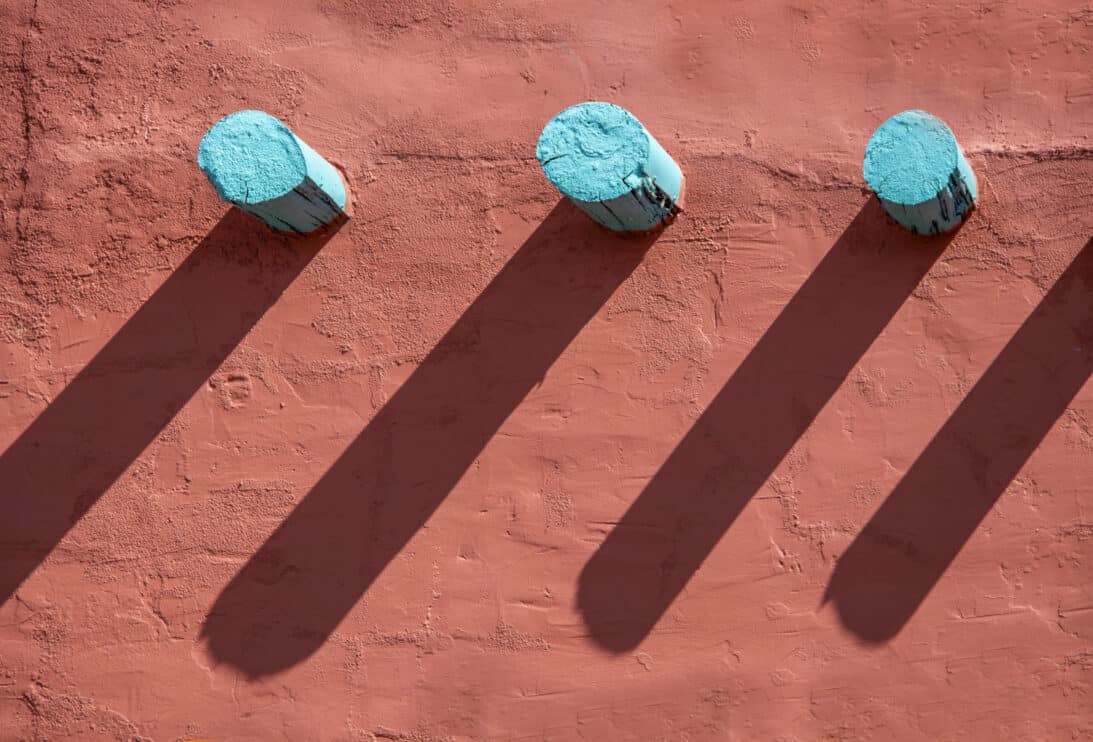 background-turquoise-corbels-and-their-long-shadows-on-an-orange-stucco-wall-on-southwestern-style-building