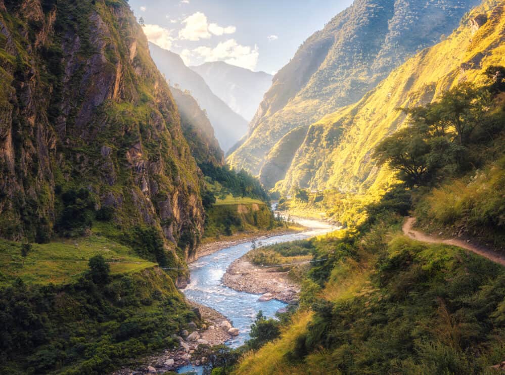colorful-landscape-with-high-himalayan-mountains-beautiful-curving-river-green-forest-blue-sky-with-clouds-and-yellow-sunlight-at-sunset-in-summer-in-nepal-mountain-valley-travel-in-himalayas