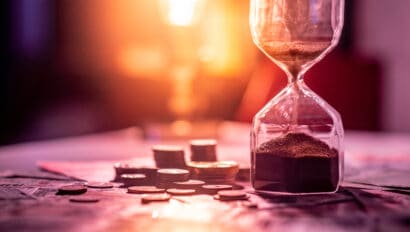 sand-running-through-the-shape-of-hourglass-on-table-with-banknotes-and-coins-of-international-currency-time-investment-and-retirement-saving-urgency-countdown-timer-for-business-deadline-concept