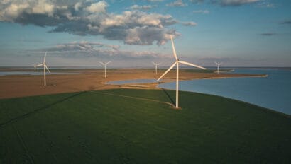 aerial-view-of-wind-turbines-and-agriculture-field-near-the-sea-at-sunset