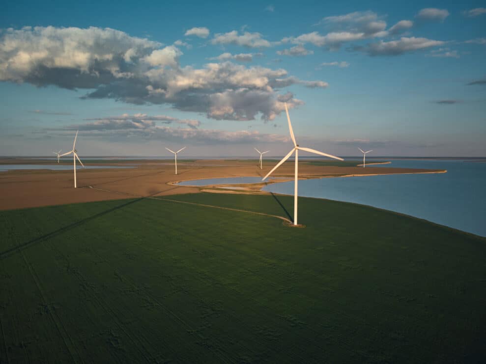 aerial-view-of-wind-turbines-and-agriculture-field-near-the-sea-at-sunset