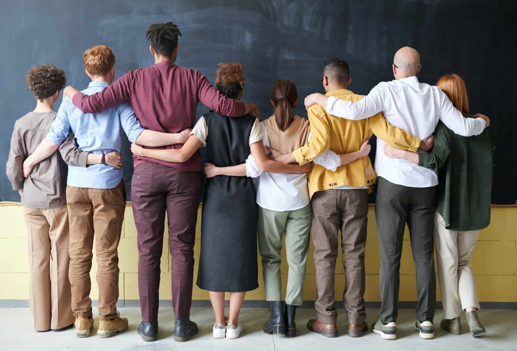 Group of people with their arms around each other.