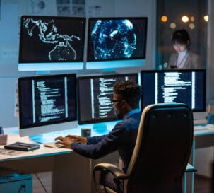 A man working at a desk with multiple monitors.