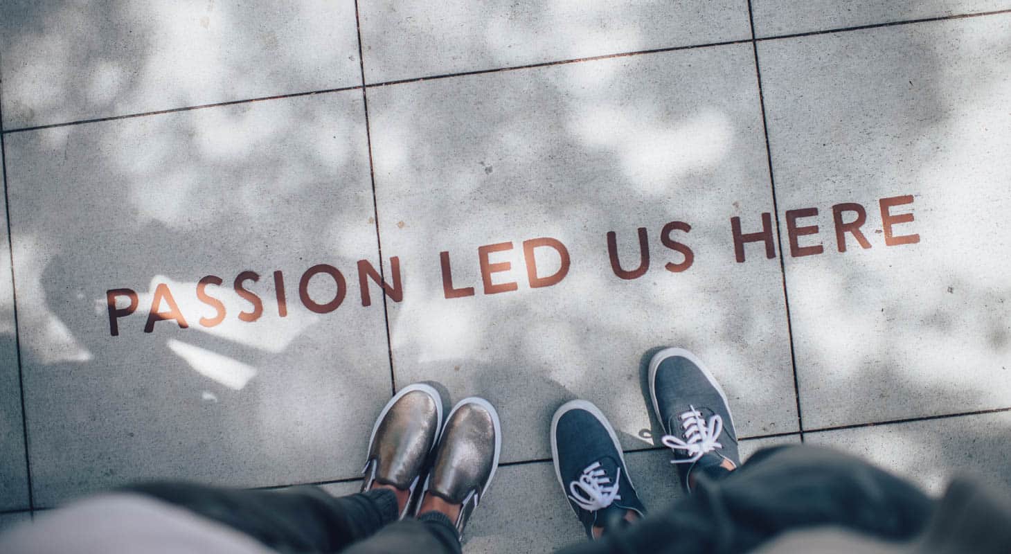 Two people standing on a sidewalk that says "Passion Led Us Here".