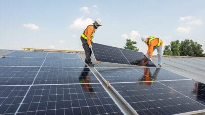 Pair of construction workers installing solar panels.