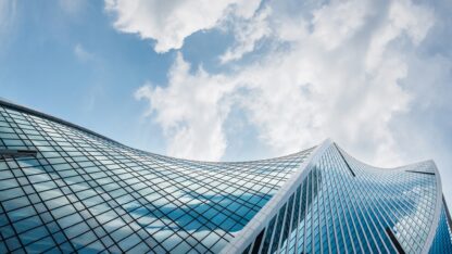 Skyward perspective of the clouds from the bottom of a skyscraper.