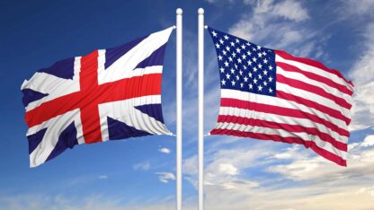 The flags of the United Kingdom of Great Britain and Northern Ireland as well as the United States of America raised up on flagpoles.