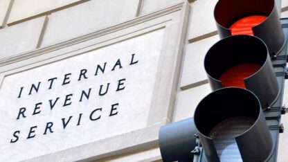 A stoplight on red mounted in front of an Internal Revenue Service building.