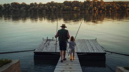 Two generations, grandparent and grandchild, stepping out onto a dock to go fishing