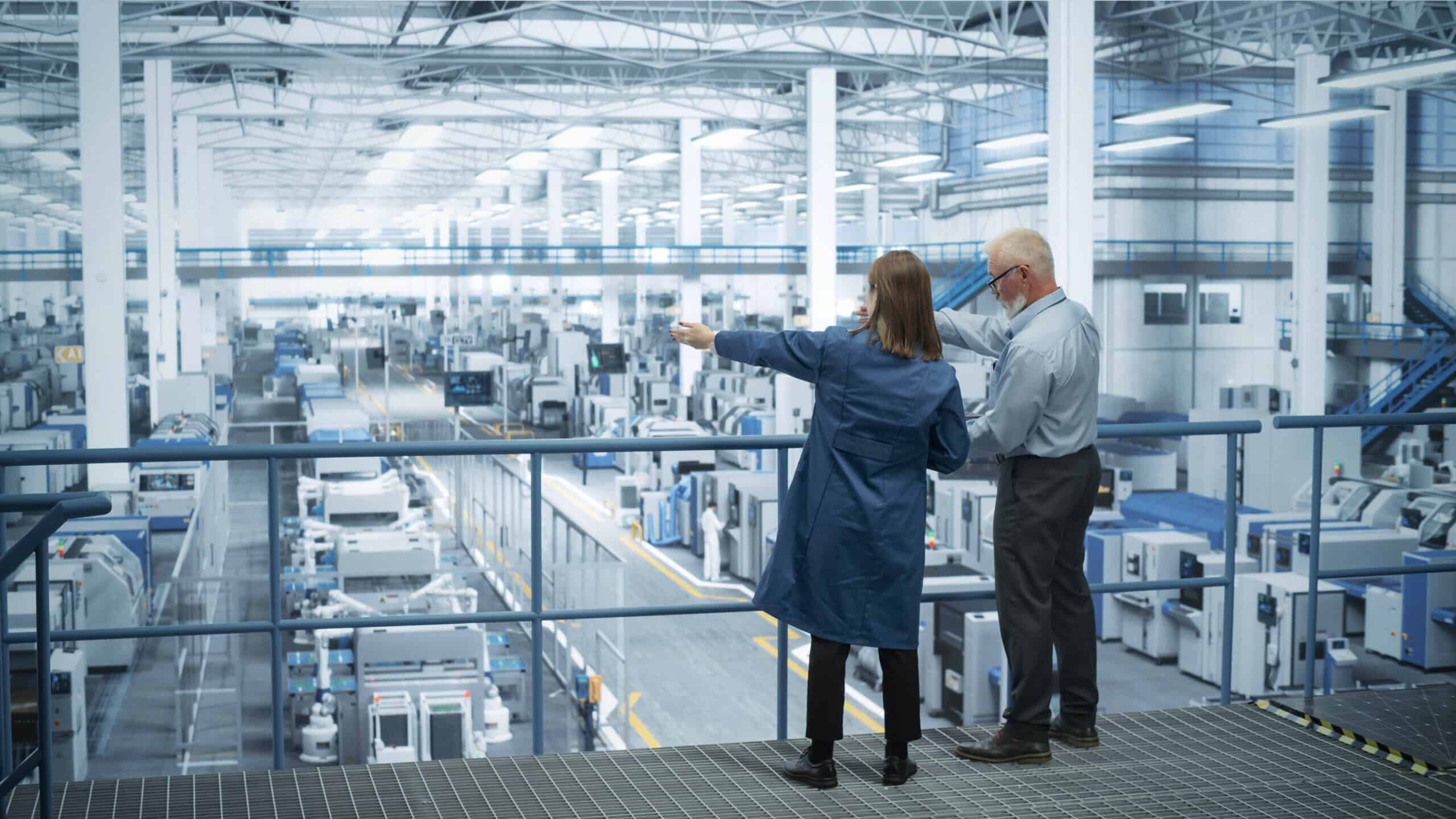 Business leaders in a manufacturing facility discussing mergers and acquisitions