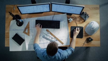 Top View of a Technical Engineer Working on His Blueprints