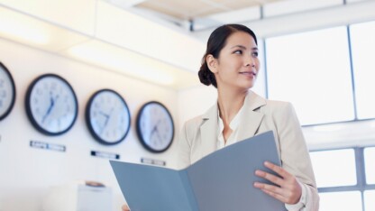 Businesswoman standing in front of multiple international clocks representing the new international tax landscape facing multinational companies