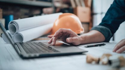 Engineering working with drawings inspection on laptop in the office