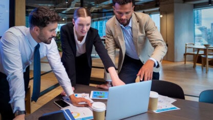 Group of business professionals gathered around a computer screen, considering SOC 2 reporting