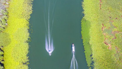 Two boats speeding past one another in a river representing the merger of a parent corporation into a subsidiary corporation treated as a downstream reorganization