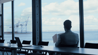 Business leader looking out window of conference room overlooking water, representing global business concerns related to controlled foreign corporations (CFCs)