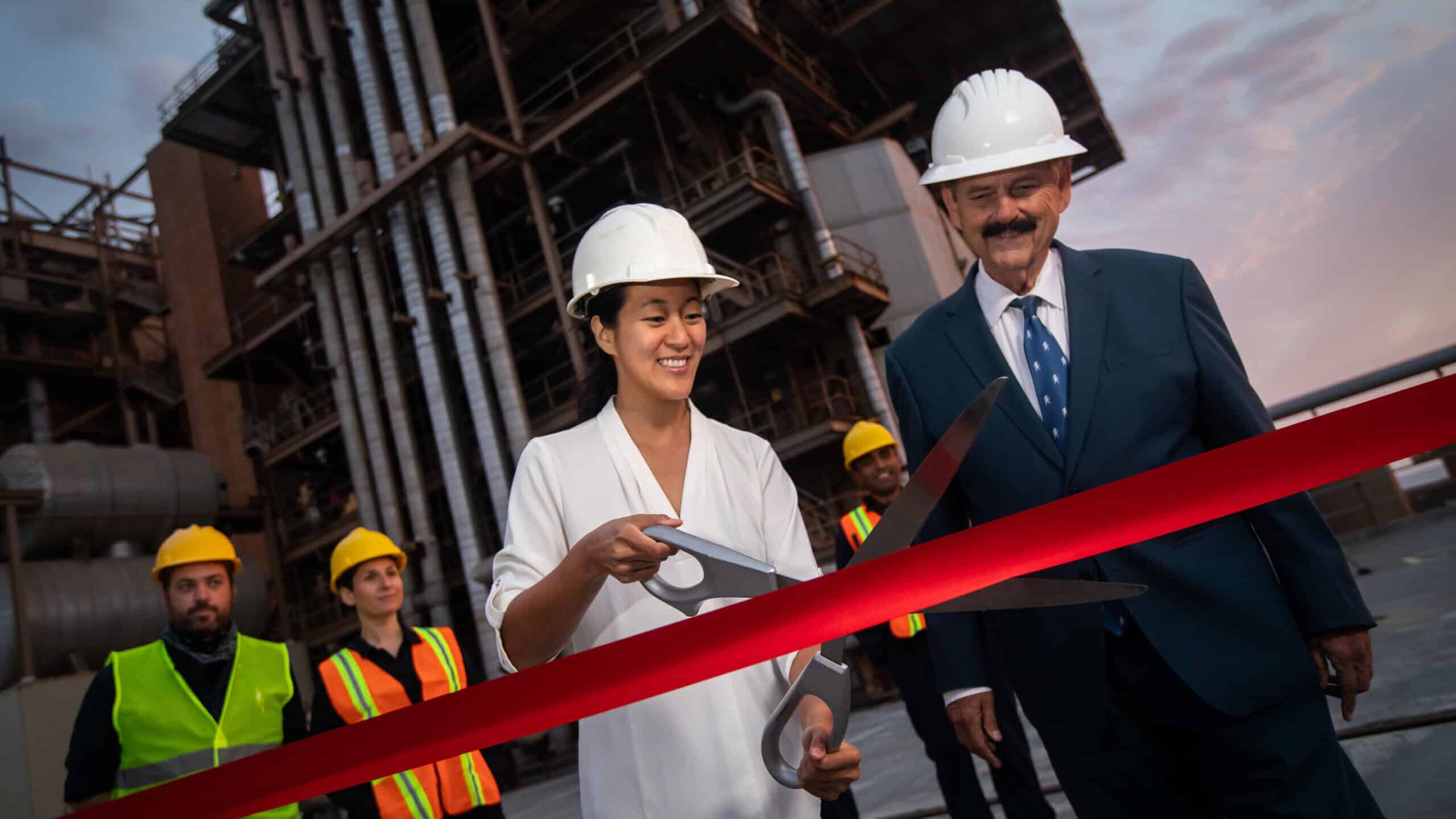 Company leaders cutting ribbon with oversized scissors