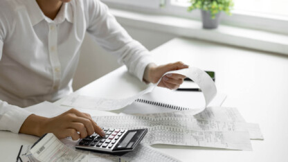 Person totaling receipts with a calculator