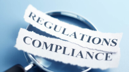 magnifying glass with two strips of paper saying regulations and compliance